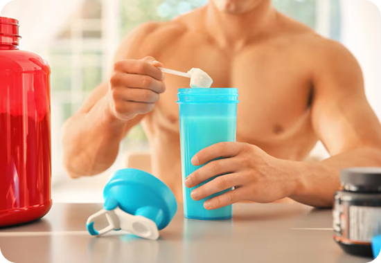 Man preparing a protein shake with a blue shaker bottle on a table.