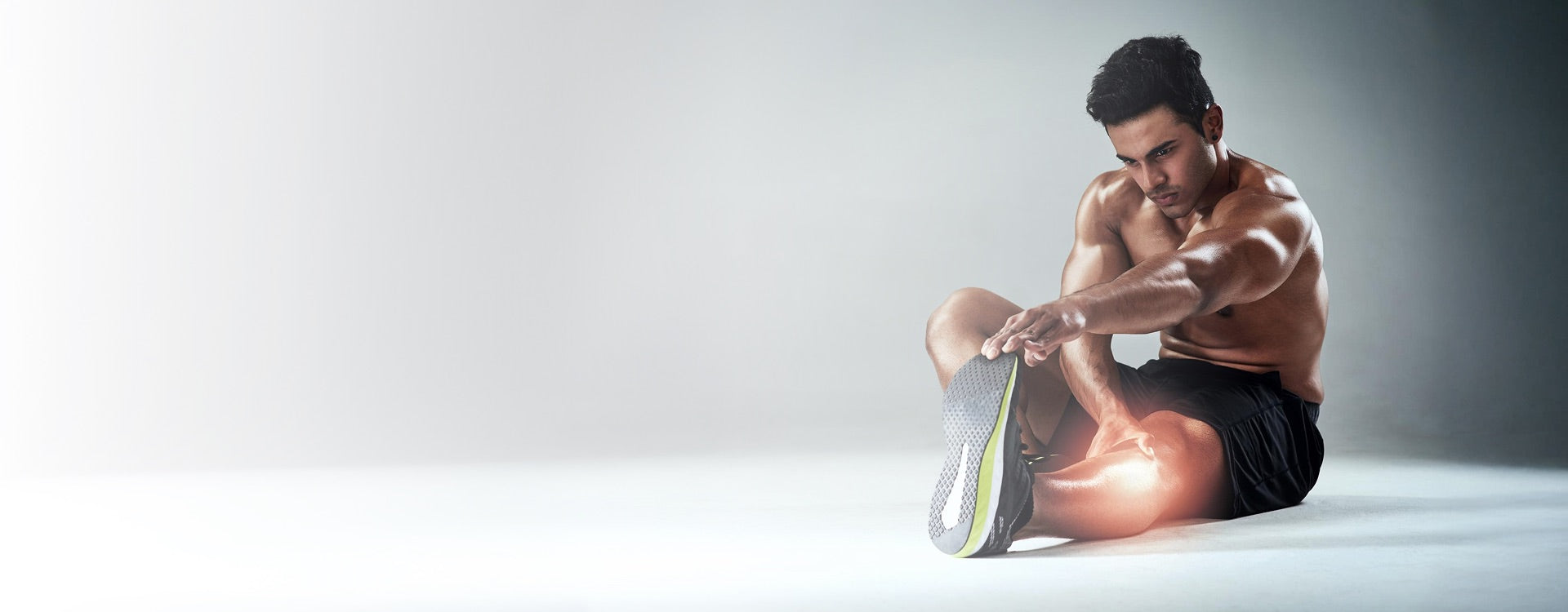 Man stretching his leg on a light gray background