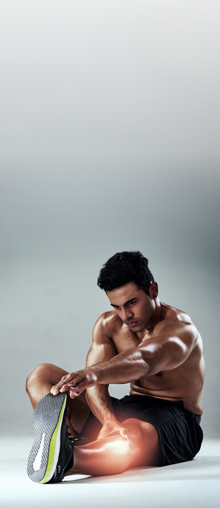 Man stretching his leg on a light gray background